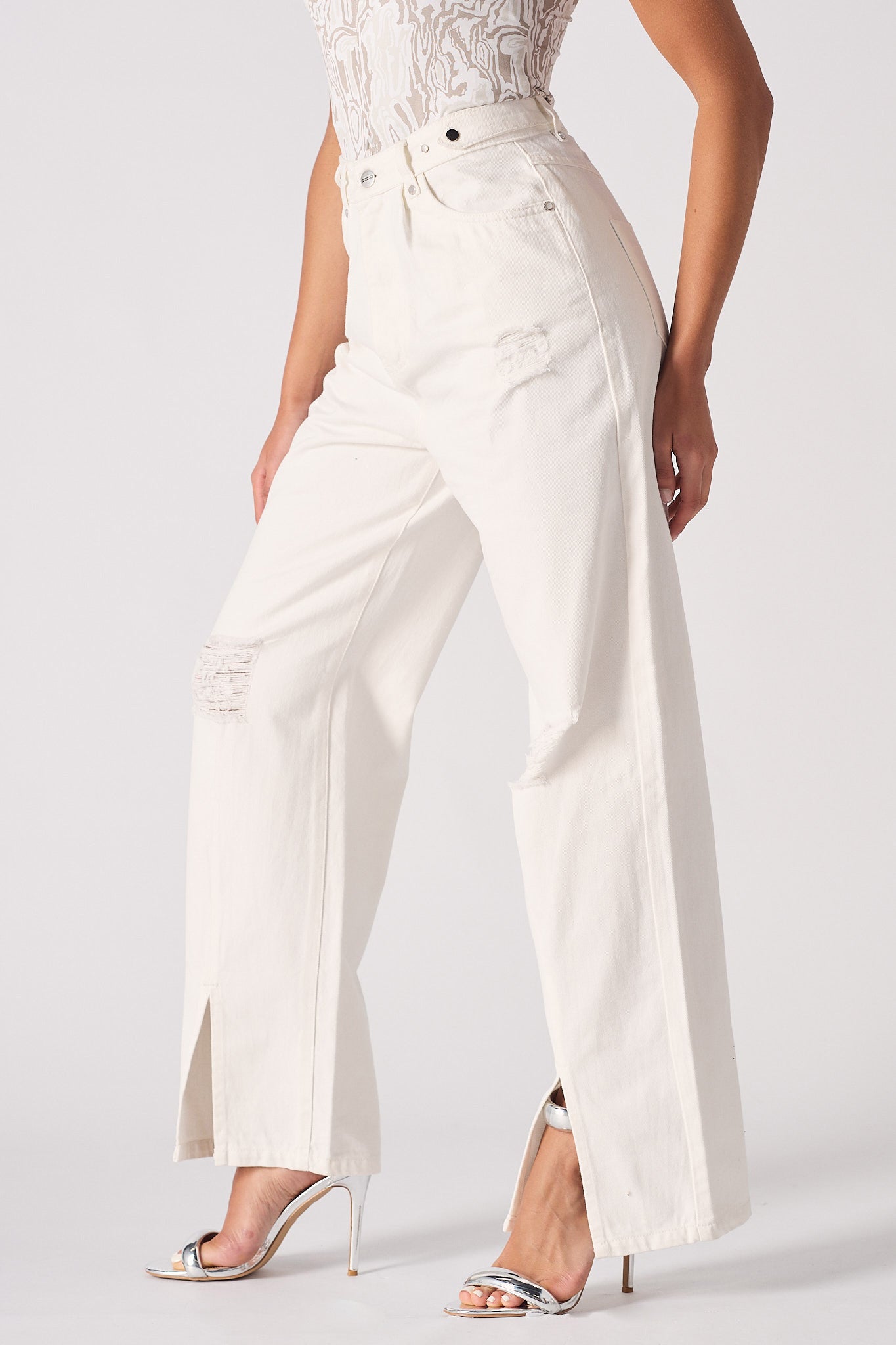 Side view of the women's white distressed wide-leg jeans with a side split hem.