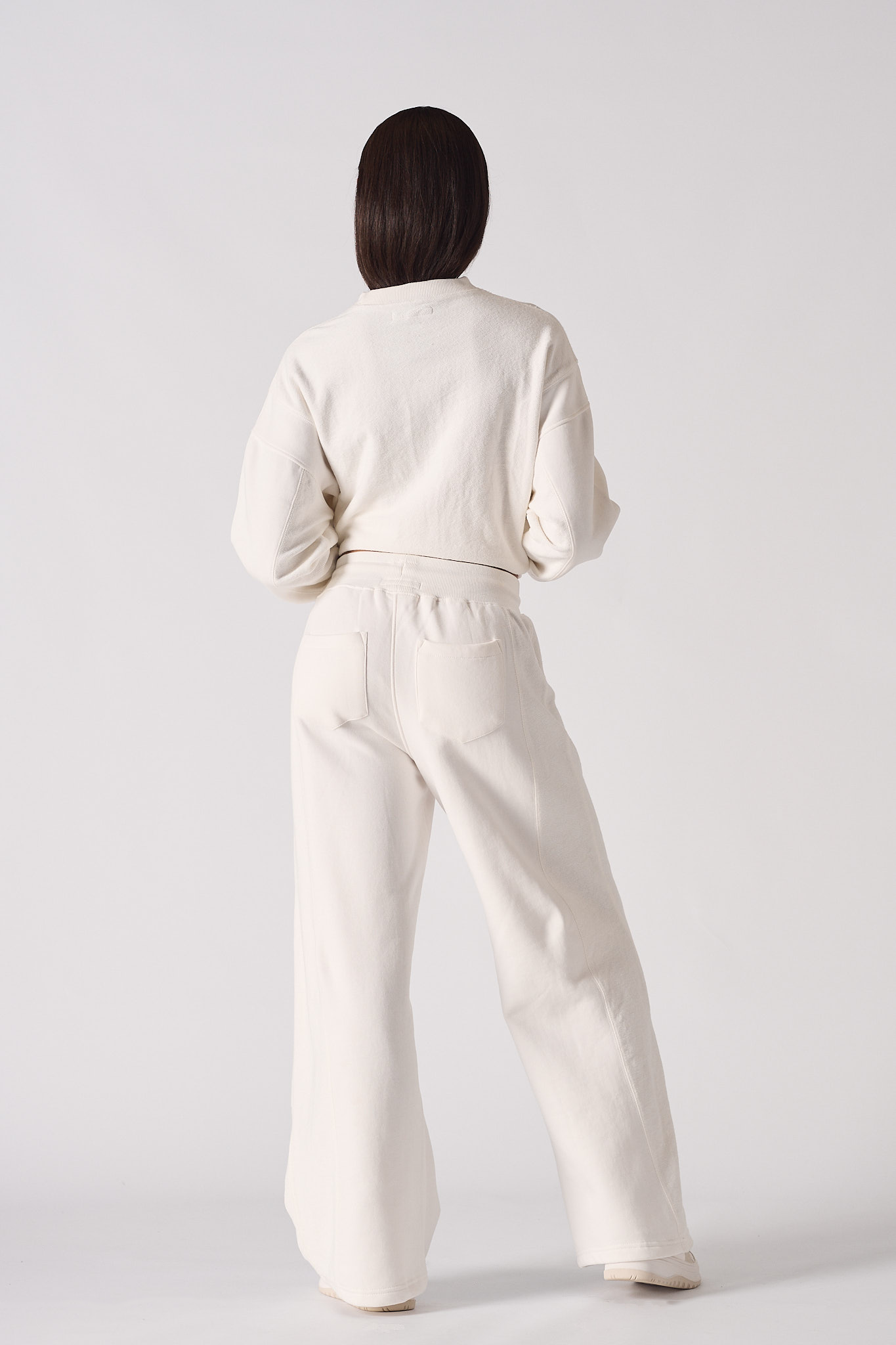 Back view of a model wearing the white wide-leg joggers and matching jumper.