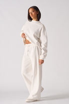 Side profile of a model wearing the white wide-leg joggers for women.