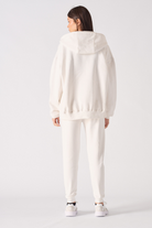Back view of a model in the women's white zip-up hoodie and matching joggers.