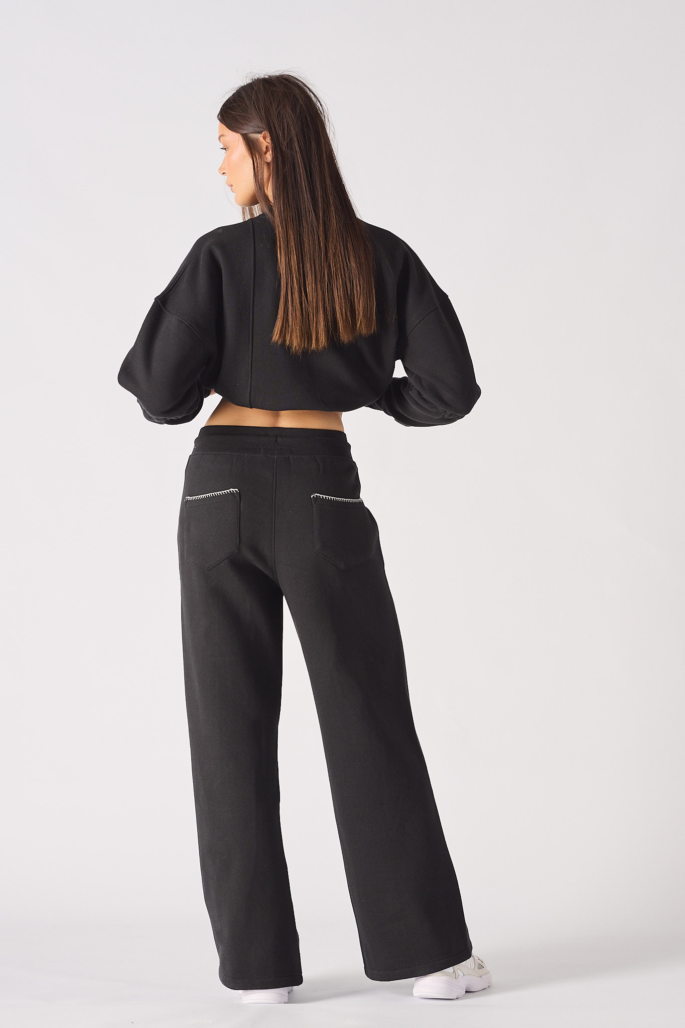 Close up of the HERMAN logo patch on the leg of black wide leg joggers