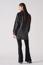 Back view of a model wearing the women's acid washed denim shirt.