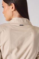 Close-up of the metal logo tag on the back of the women's beige shirt dress.