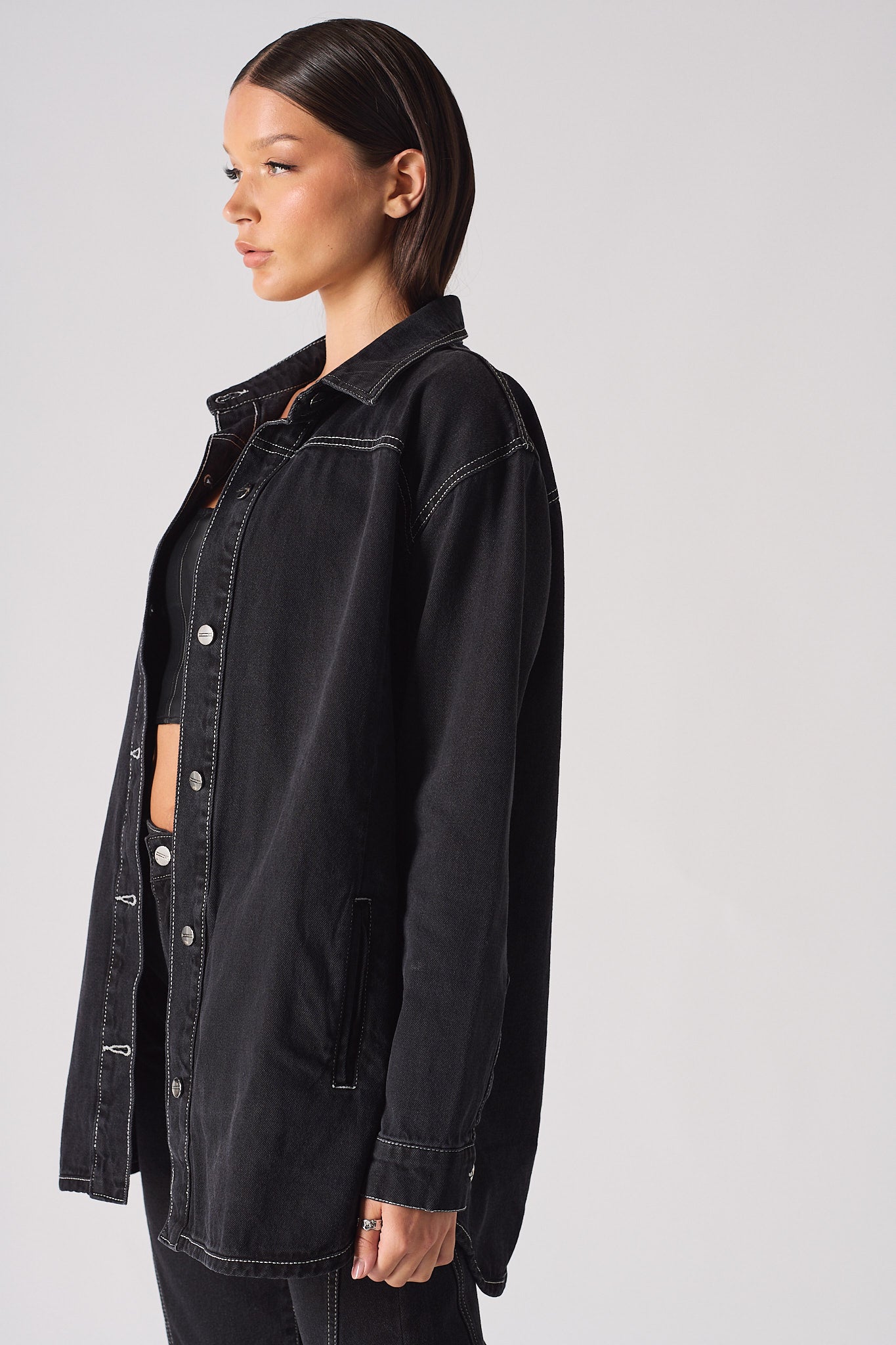 Side view of the women's black denim shirt showing the contrast stitch detail.