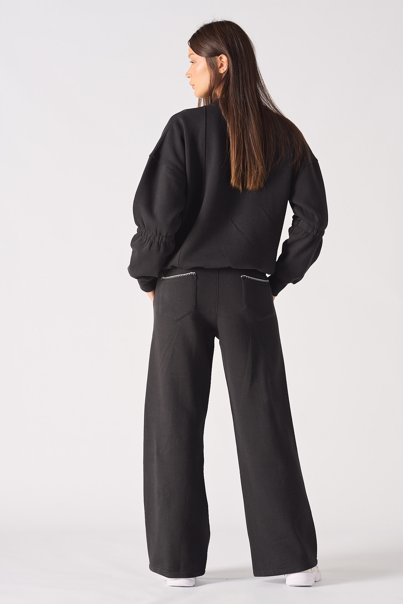 Back view of a model in the women's black jumper and wide-leg joggers set.