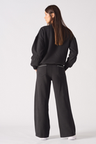 Back view of a model in the women's black jumper and wide-leg joggers set.