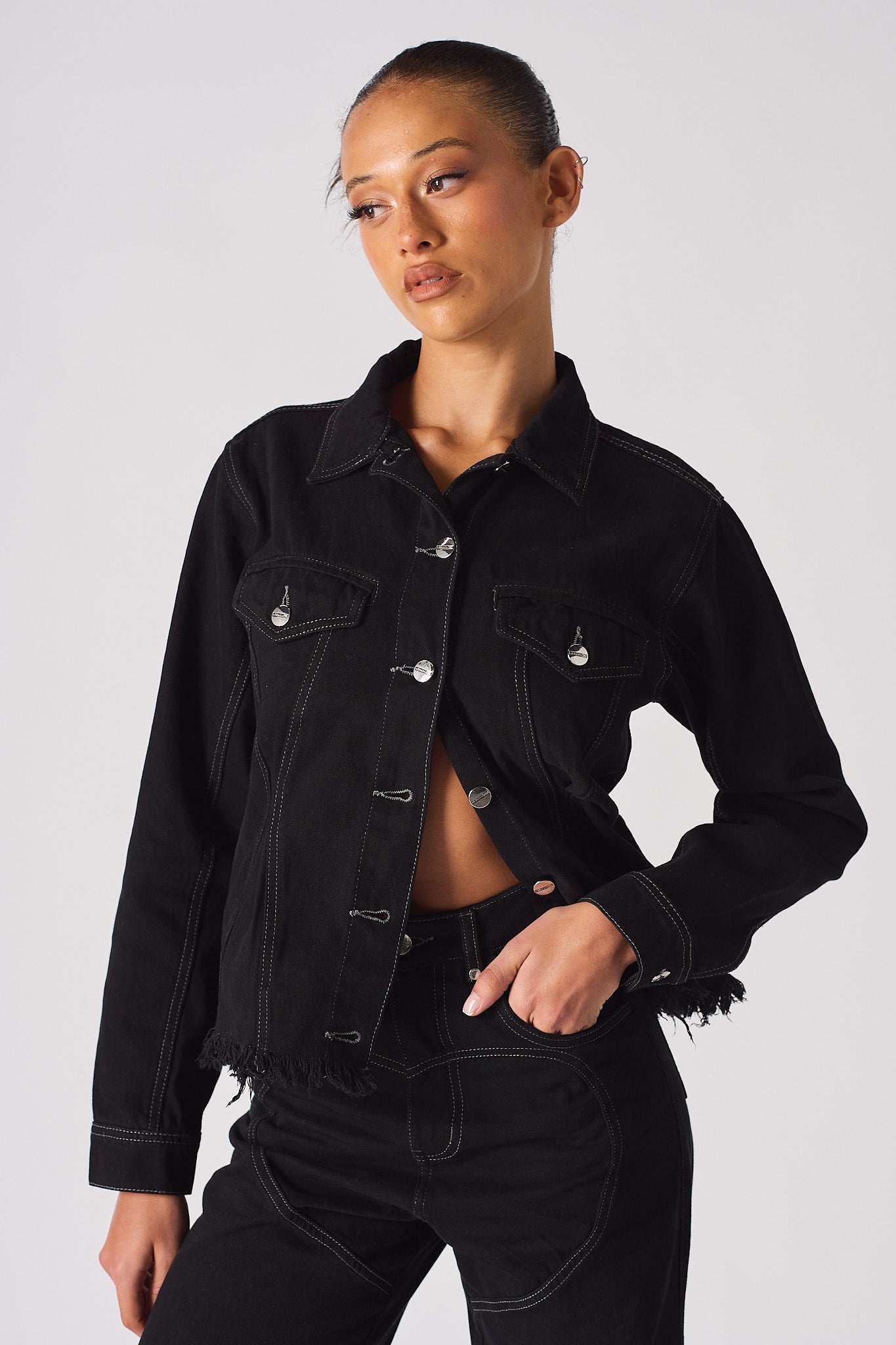 A model wearing the women's black tapered waist denim jacket.