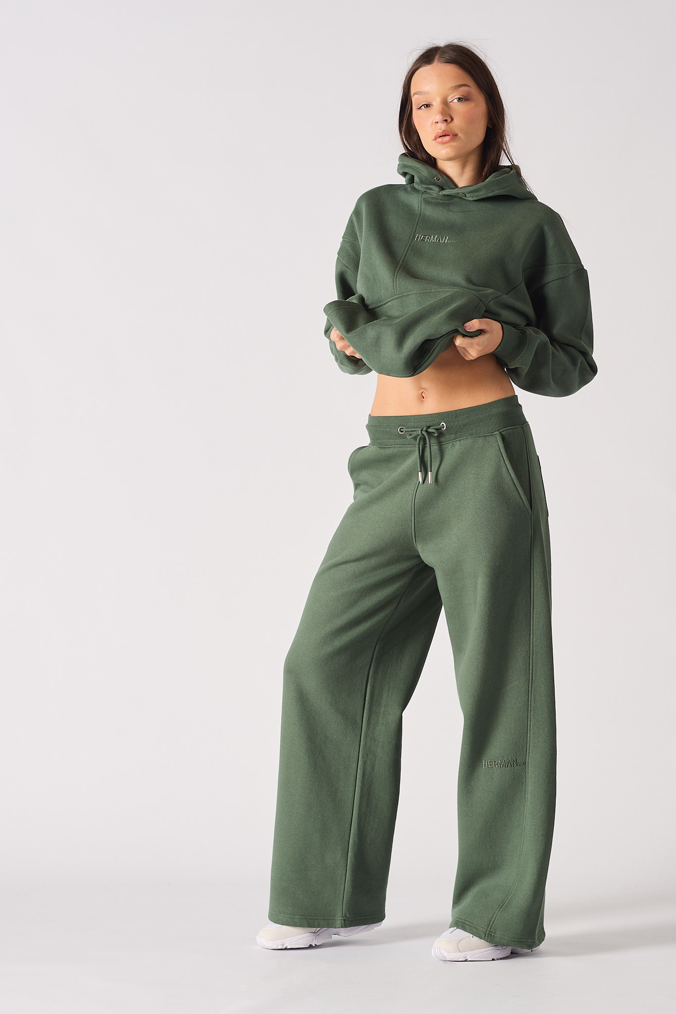 A model styled in the women's dark green wide-leg joggers and a matching hoodie.