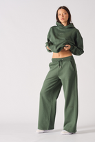 A model styled in the women's dark green wide-leg joggers and a matching hoodie.