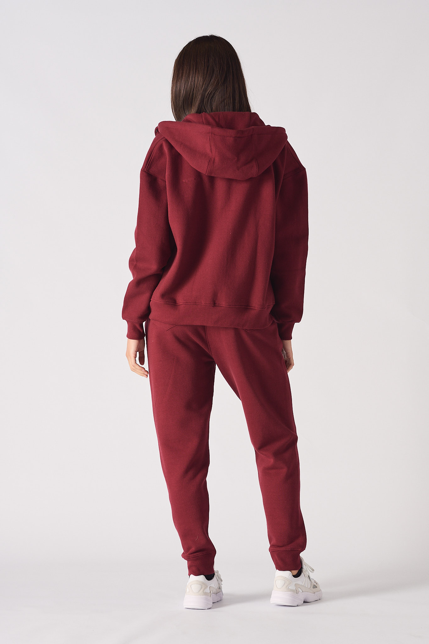 Back view of a model in the women's red zip-up hoodie and tracksuit.