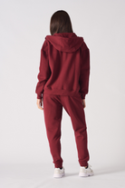 Back view of a model in the women's red zip-up hoodie and tracksuit.