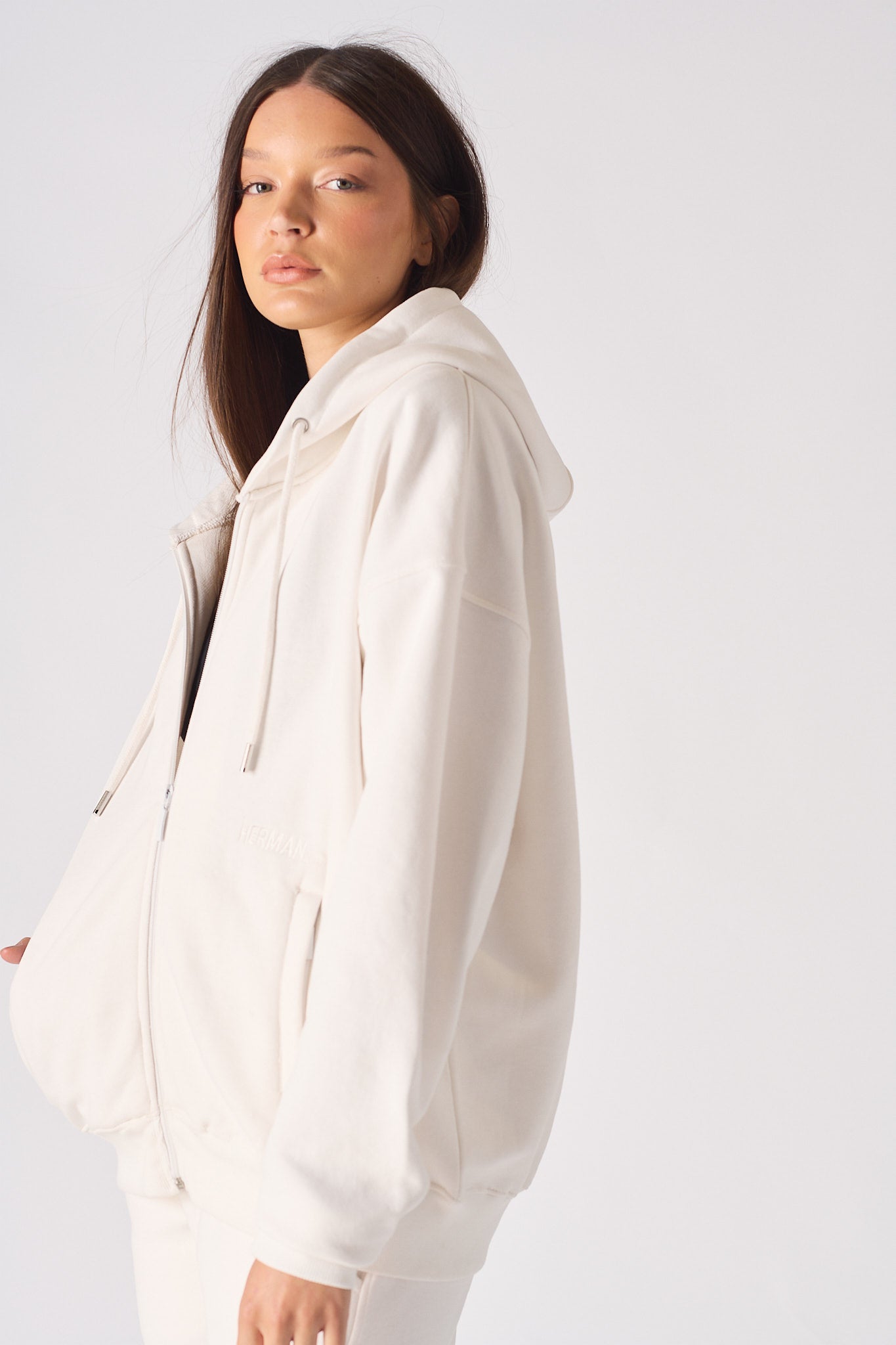 Side profile of a model wearing the women's white zip-up hoodie.