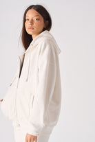Side profile of a model wearing the women's white zip-up hoodie.