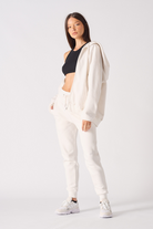 A model styled in the women's white zip-up hoodie, worn open.