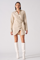 Front view of a model wearing the women's beige cotton asymmetric shirt dress.