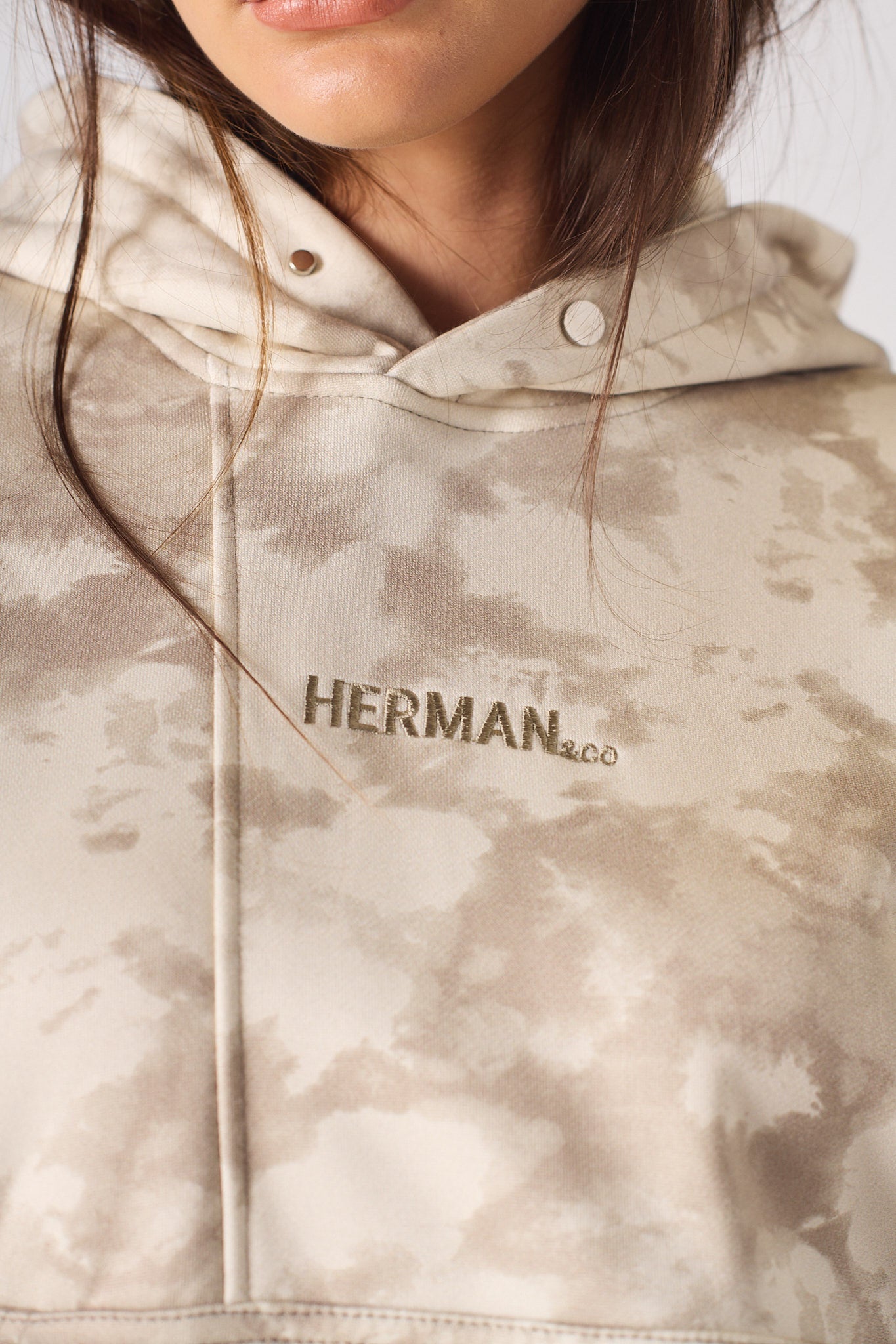Detailed close up of the ribbed sleeve cuff and abstract print on beige hoodie