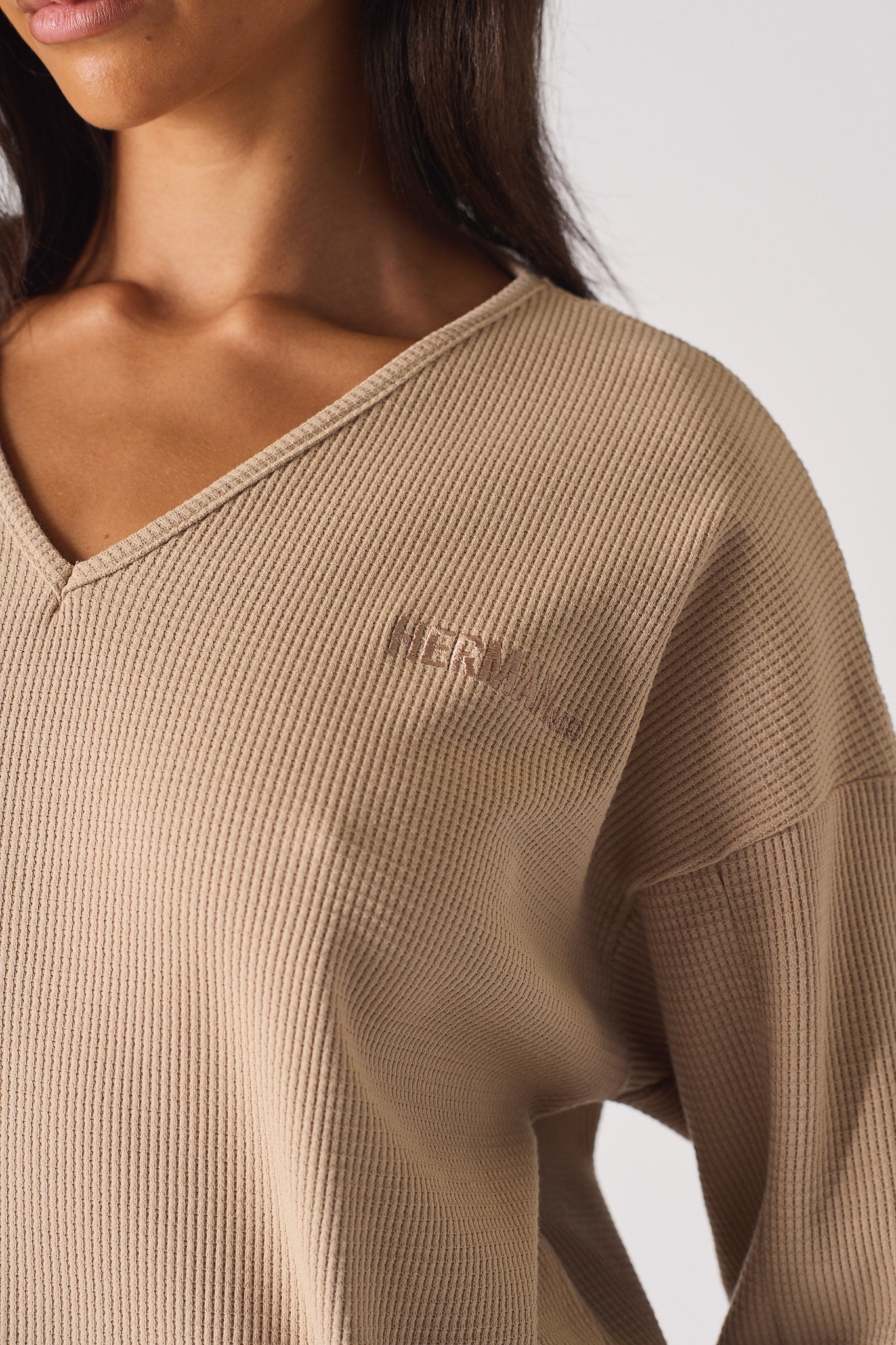 Close up detail of the ribbed sleeve cuff on beige v neck jumper