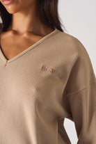 Close up detail of the ribbed sleeve cuff on beige v neck jumper