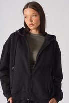 Model wearing a casual black zip up hoodie for women layered over a grey top