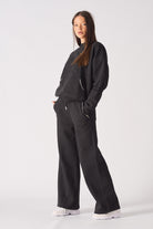Model walking in black wide leg joggers showcasing the casual streetwear drape