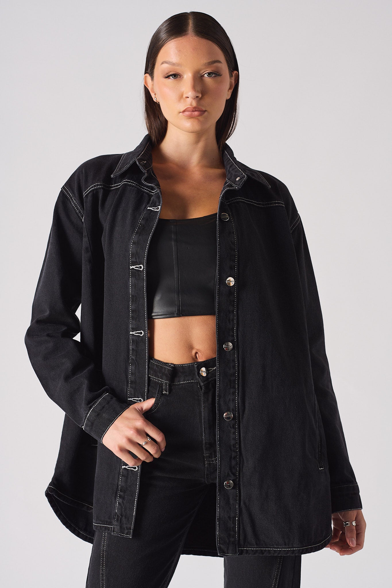 A model wearing the women's black oversized denim shirt with contrast stitching.