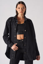 A model wearing the women's black oversized denim shirt with contrast stitching.