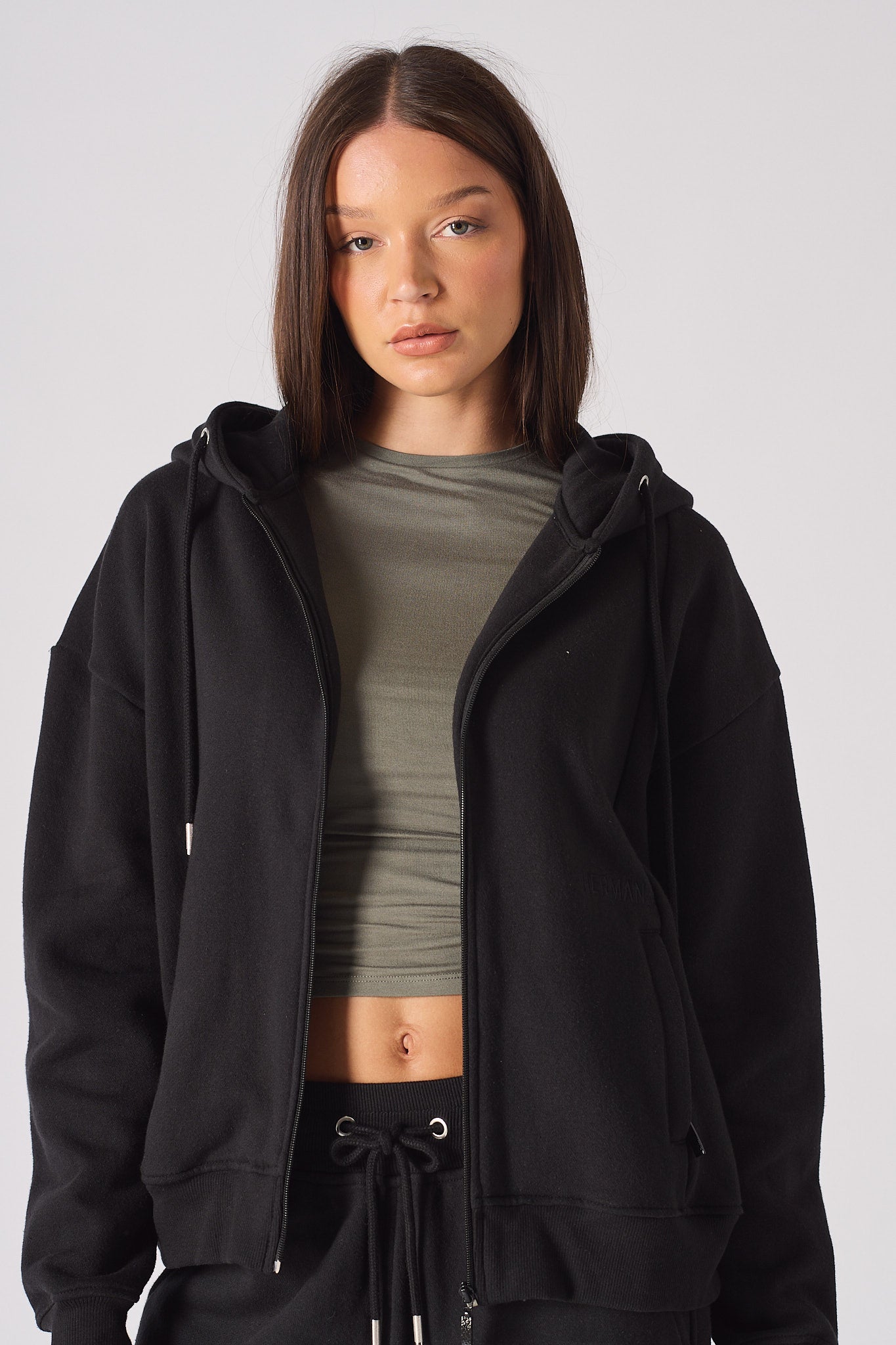 Side view of model with hands in pockets of black zip up hoodie womens