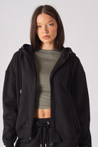Side view of model with hands in pockets of black zip up hoodie womens