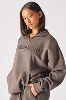 Model posing in a casual brown half zip women's sweatshirt and trouser set