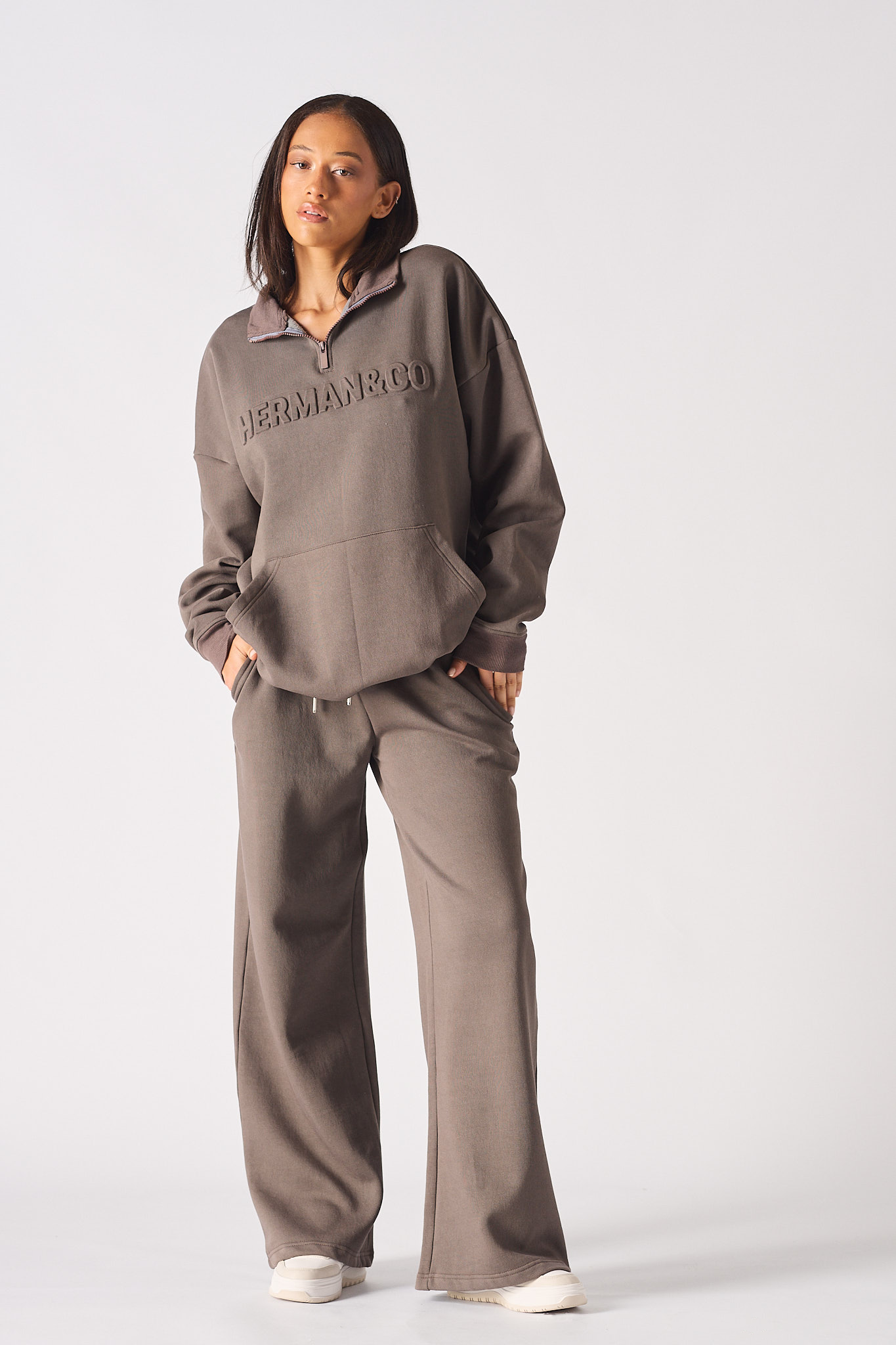 Front view of model wearing brown half zip women's sweatshirt with matching wide leg trousers