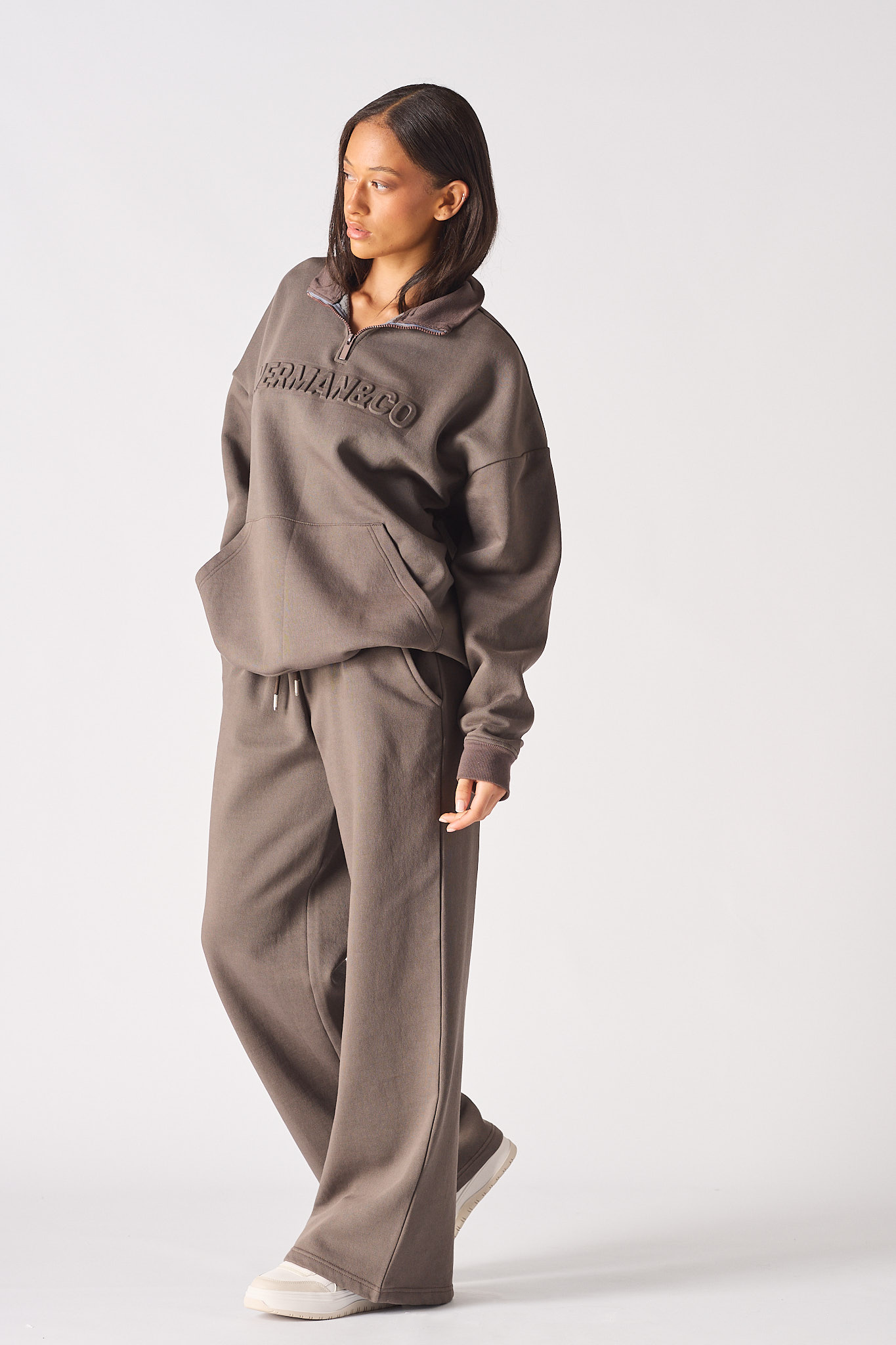 Side profile view showing the loose fit of the brown half zip women's sweatshirt