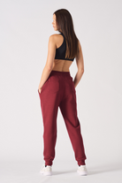 Model wearing open burgundy zip hoodie and matching tapered joggers