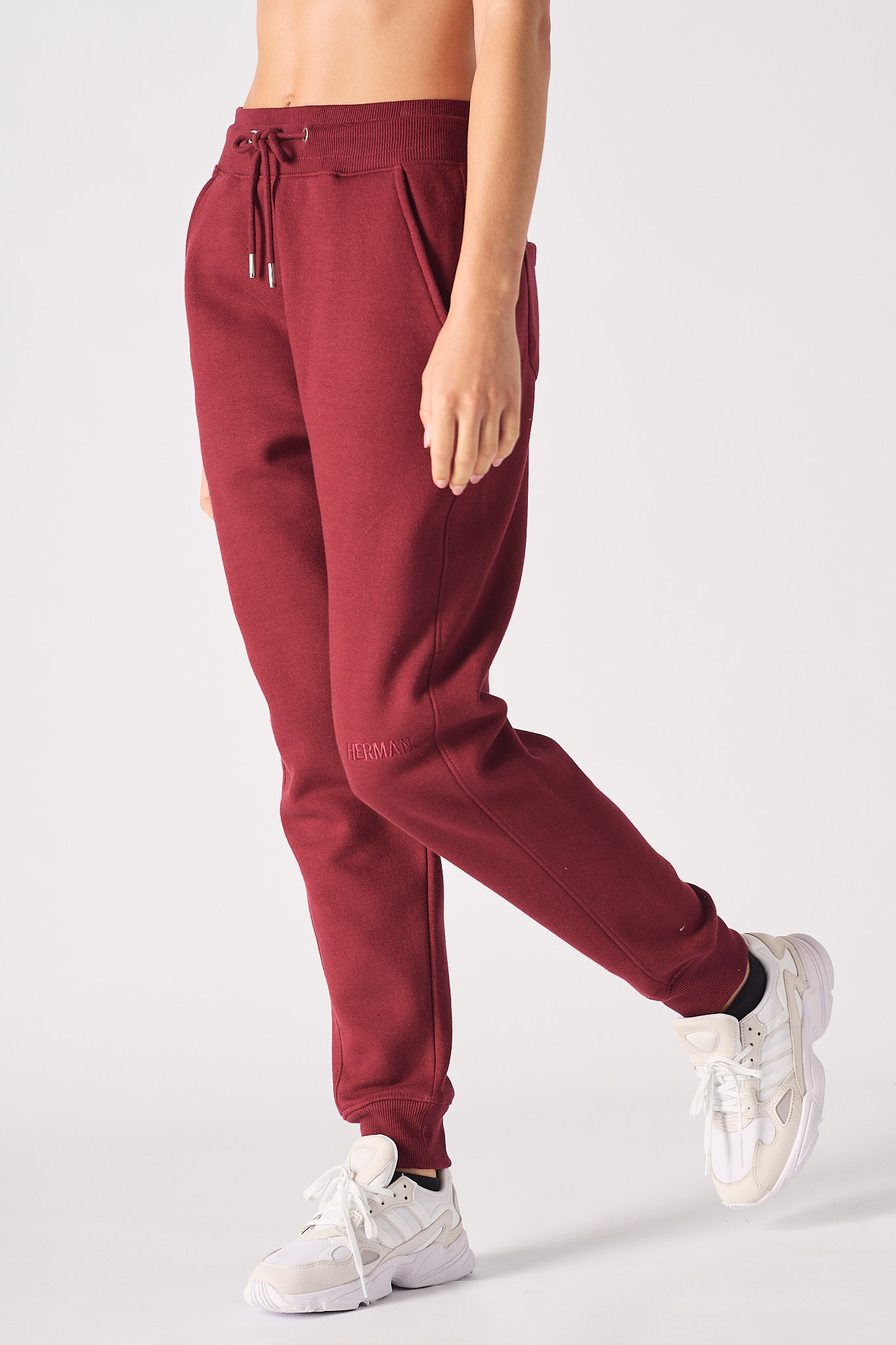 Front view of women wearing burgundy tapered joggers with hands in pockets