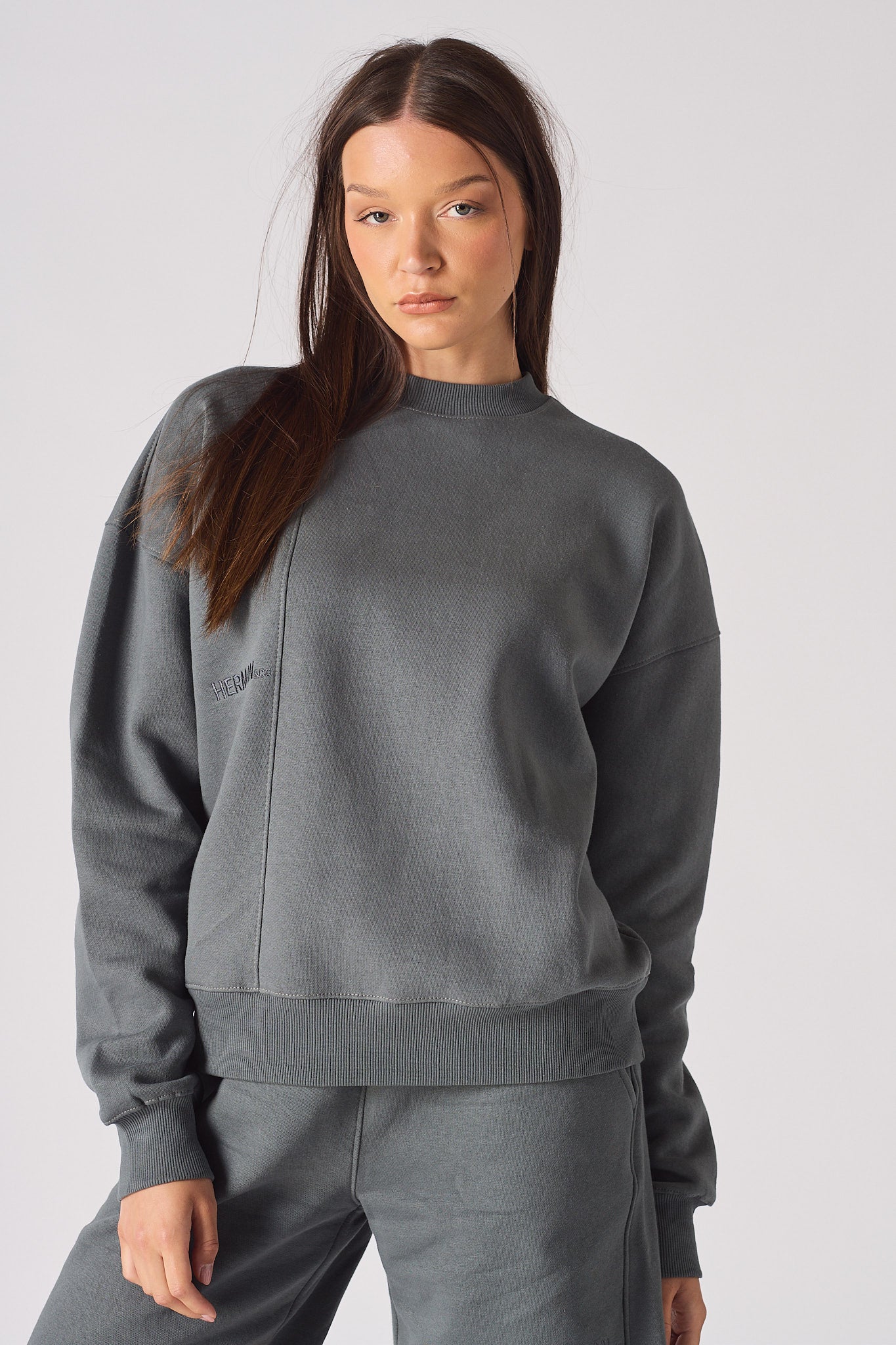 Model standing in a relaxed pose wearing oversized grey crew neck sweater