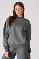 Model standing in a relaxed pose wearing oversized grey crew neck sweater