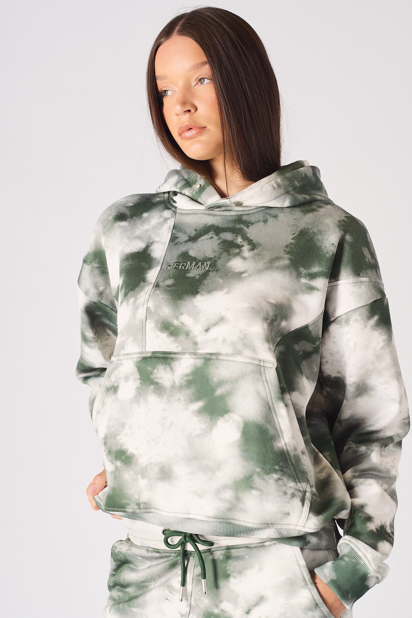 Front view of model with hands in pocket wearing womens tie dye dark green hoodie