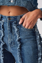 Close-up of the front pocket and frayed seam on the women's distressed jeans.