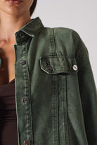 Close-up of the shoulder and button details on the women's green denim shirt.