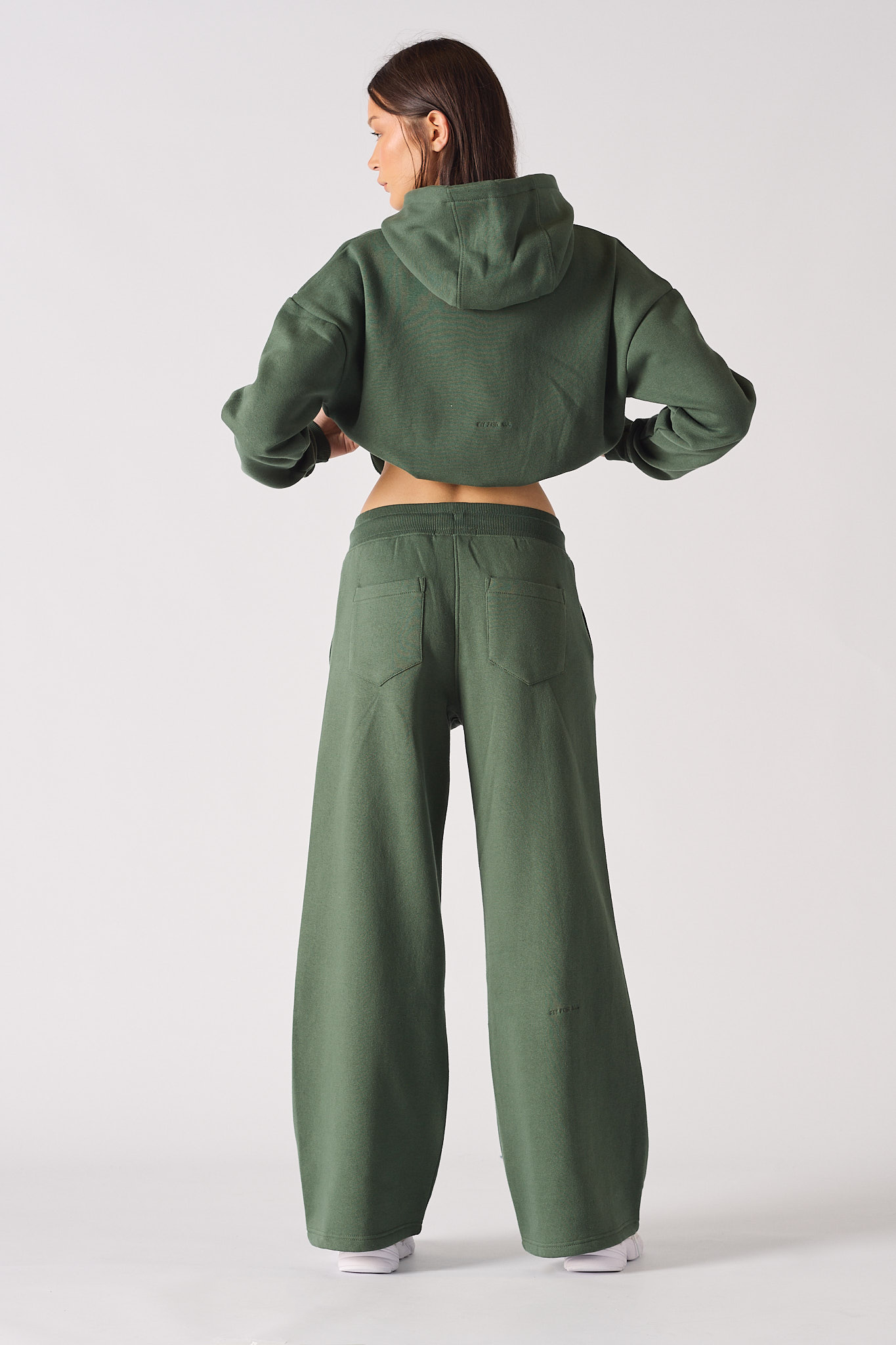 Back view of a model wearing the women's green joggers and cropped hoodie set.