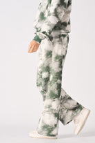 Side profile of a model walking in the women's green tie-dye wide-leg joggers.