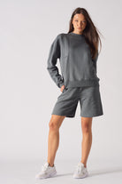 Front view of women's grey crew neck jumper styled with matching shorts
