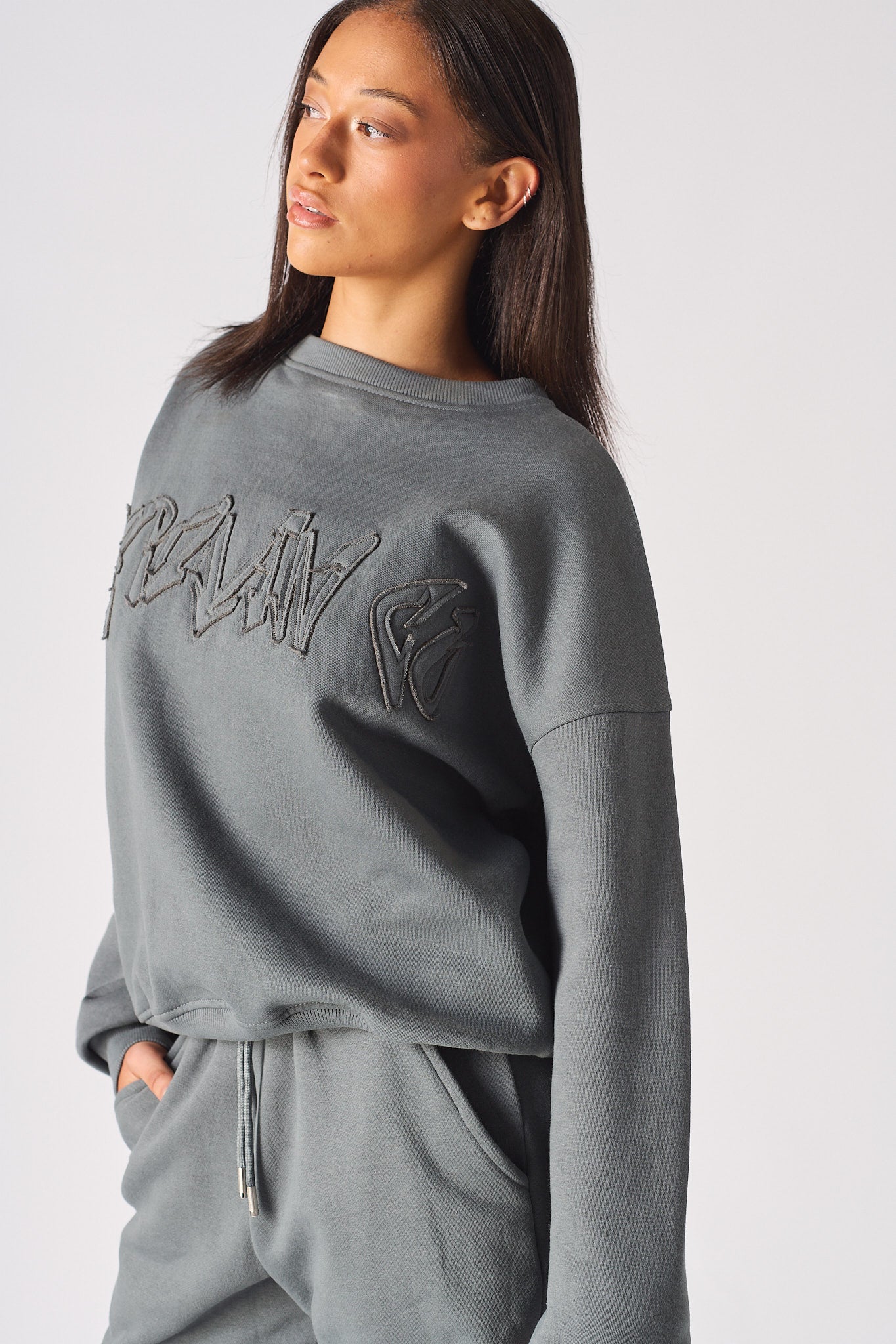 Mid shot of model wearing the embossed womens oversized grey sweatshirt in a casual stance