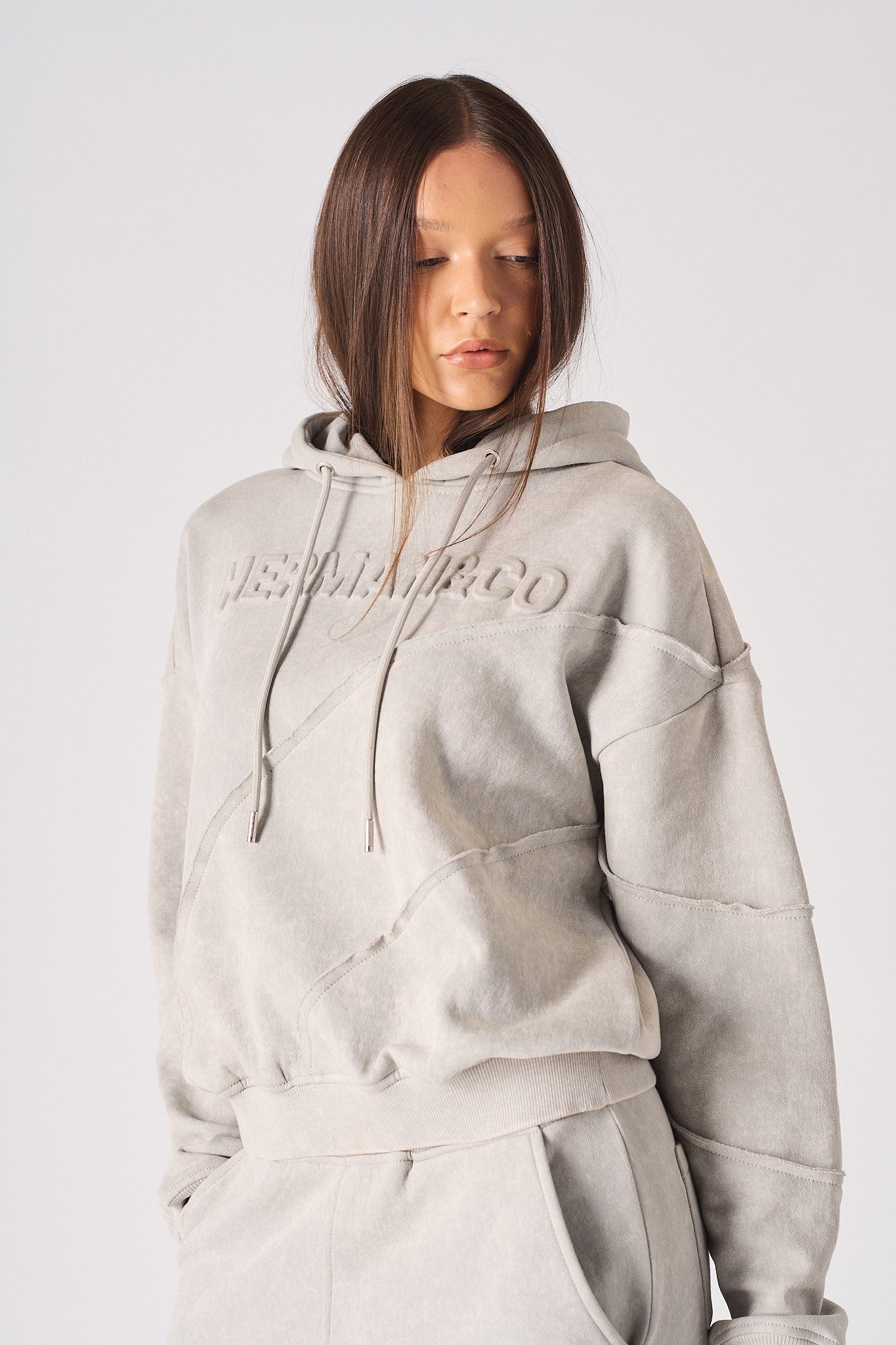 Zoomed in view of the tonal embossed branding on womens oversized grey hoodie
