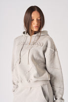 Zoomed in view of the tonal embossed branding on womens oversized grey hoodie
