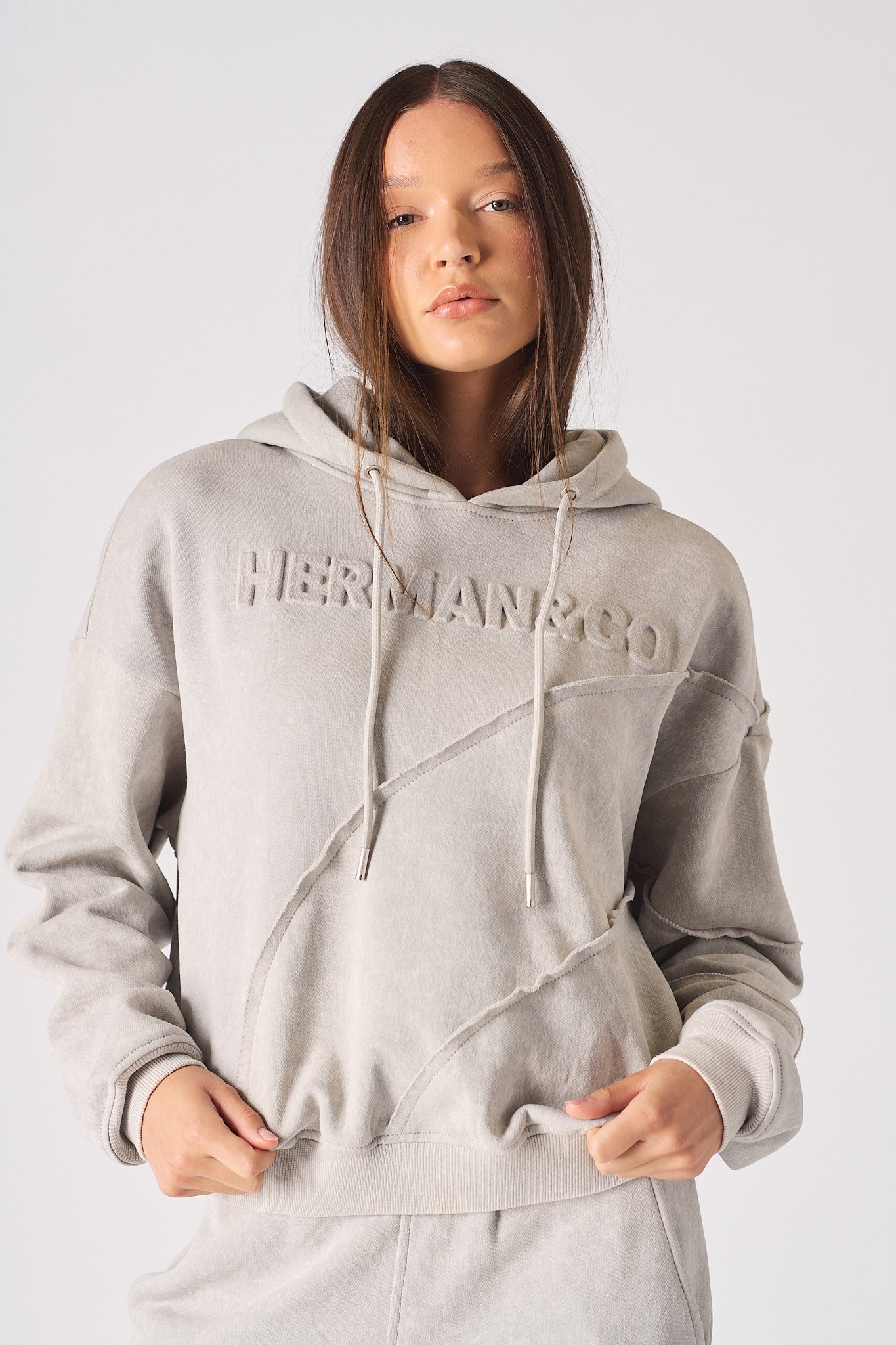 Mid shot of model wearing the embossed womens oversized grey hoodie in a casual stance