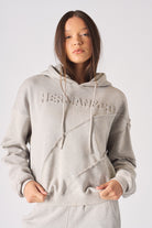 Mid shot of model wearing the embossed womens oversized grey hoodie in a casual stance