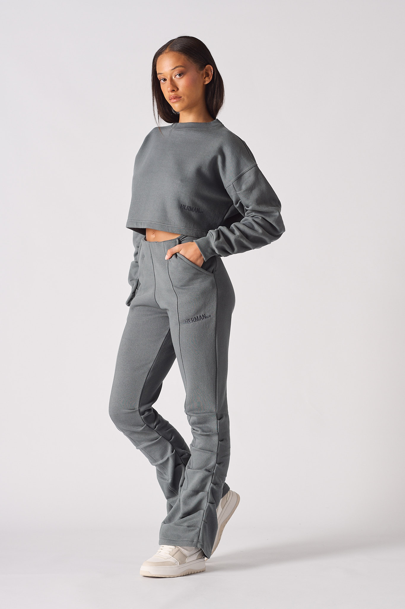 Side profile of model wearing stylish womens grey ruched flare trousers
