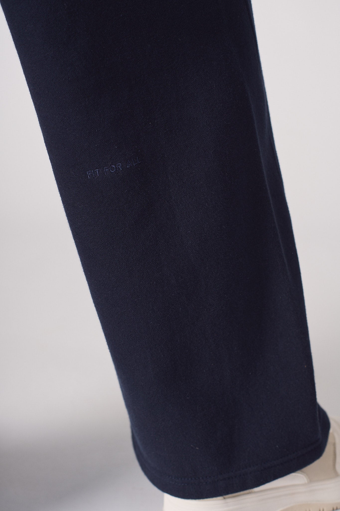 Detailed view of the embroidered logo on the leg of the women's navy joggers.