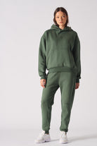 Front view of womens dark green hoodie with hands in front pocket