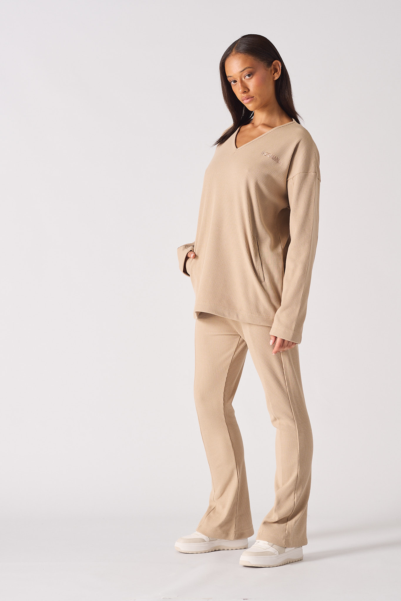 Close up showing the drop shoulder style of the beige v neck jumper